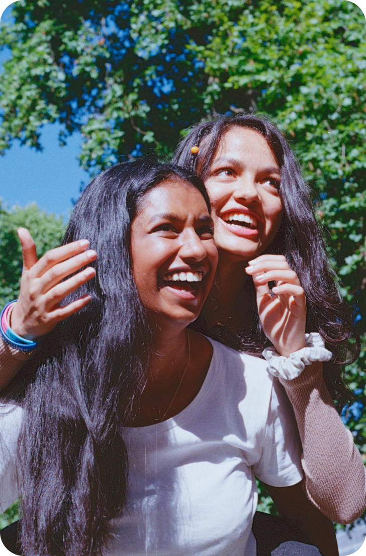 one teen girl gives another a piggy back whilst smiling